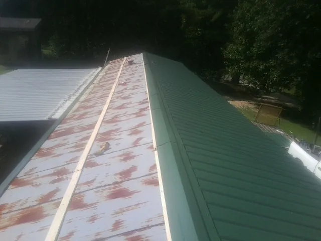 Old rusted panels beside newly installed green metal roofing — Wind Damage Roof Repair by Roofing Brothers in Xenia