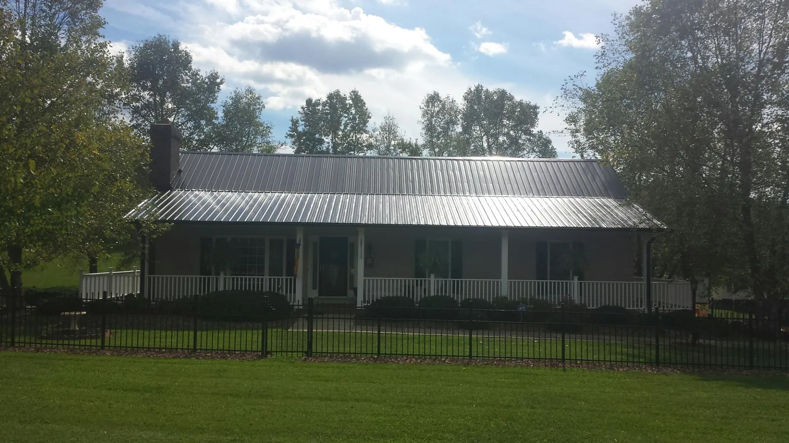 Gray metal roof on a brick ranch with a full width front porch — Gutter Guard Installation work by our crew in Xenia
