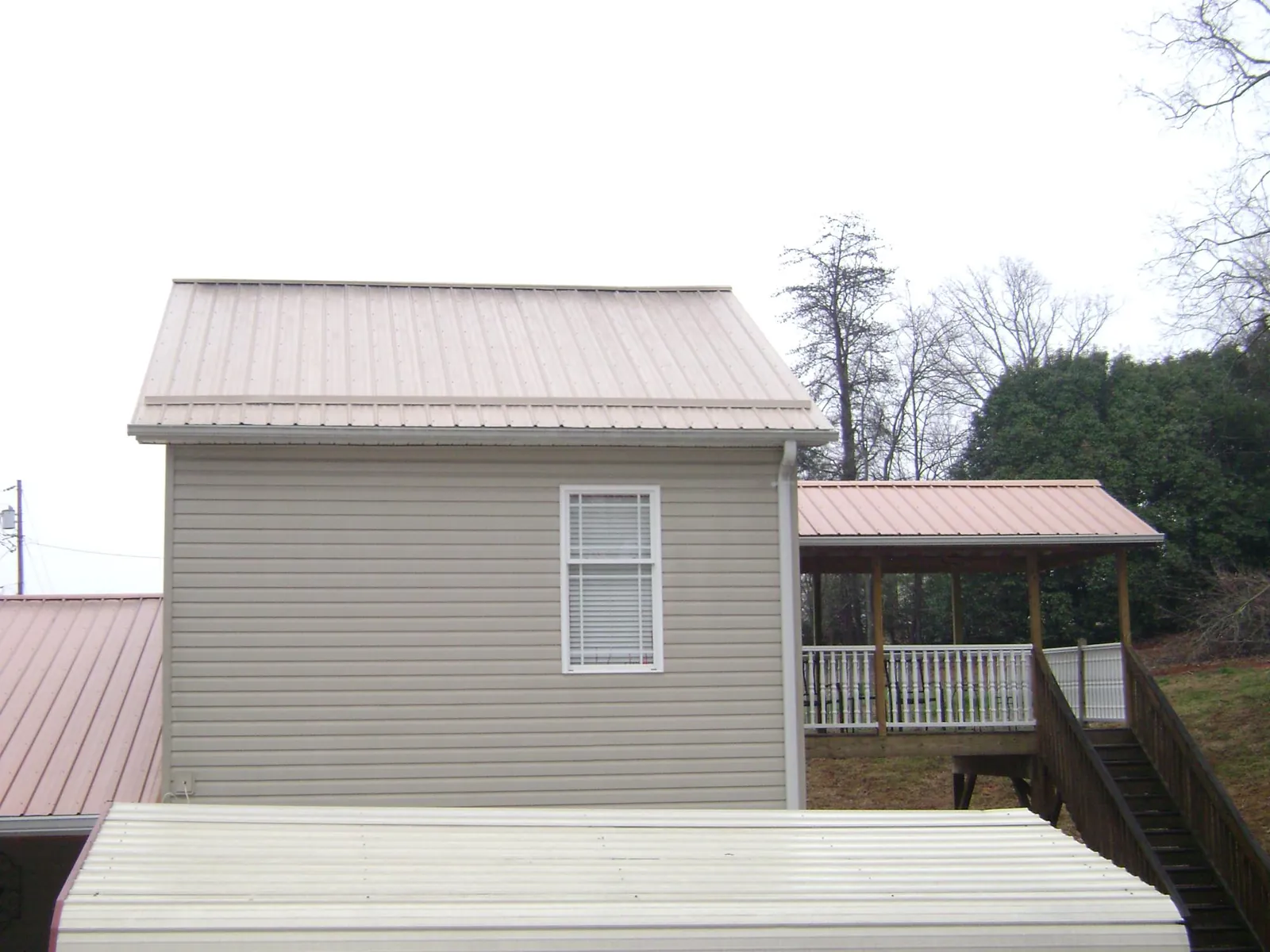 Tan metal roofs on a two story addition and attached porch, from a Roof Replacement job in Xenia