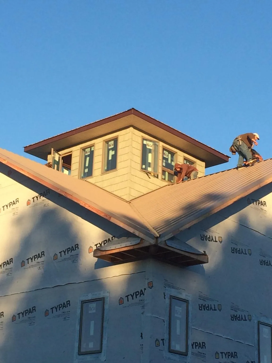 Roofers working around a rooftop cupola on a new metal roof at sunset — Roof Waterproofing in Xenia by Roofing Brothers